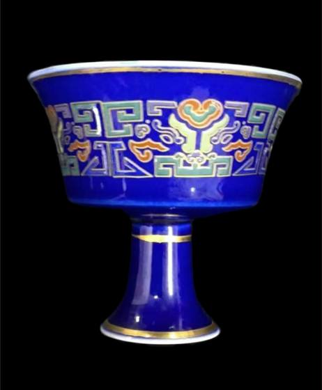 雾蓝地描金回纹如意高足杯 雾蓝地描金回纹如意高足杯，通体施浓润宝 石蓝釉，杯身饰五彩回纹与如意祥云纹样，口