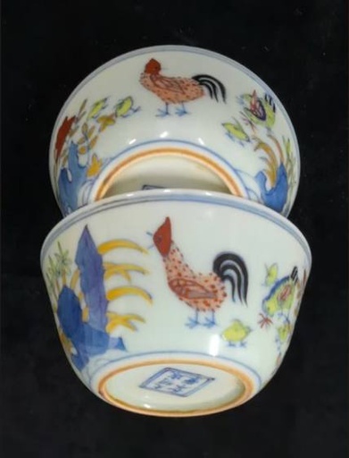 成化款斗彩鸡缸杯(一对) 此为一对成化款斗彩鸡缸杯，器型小巧圆 润，胎质细腻坚致，釉面莹润白皙。杯外壁通